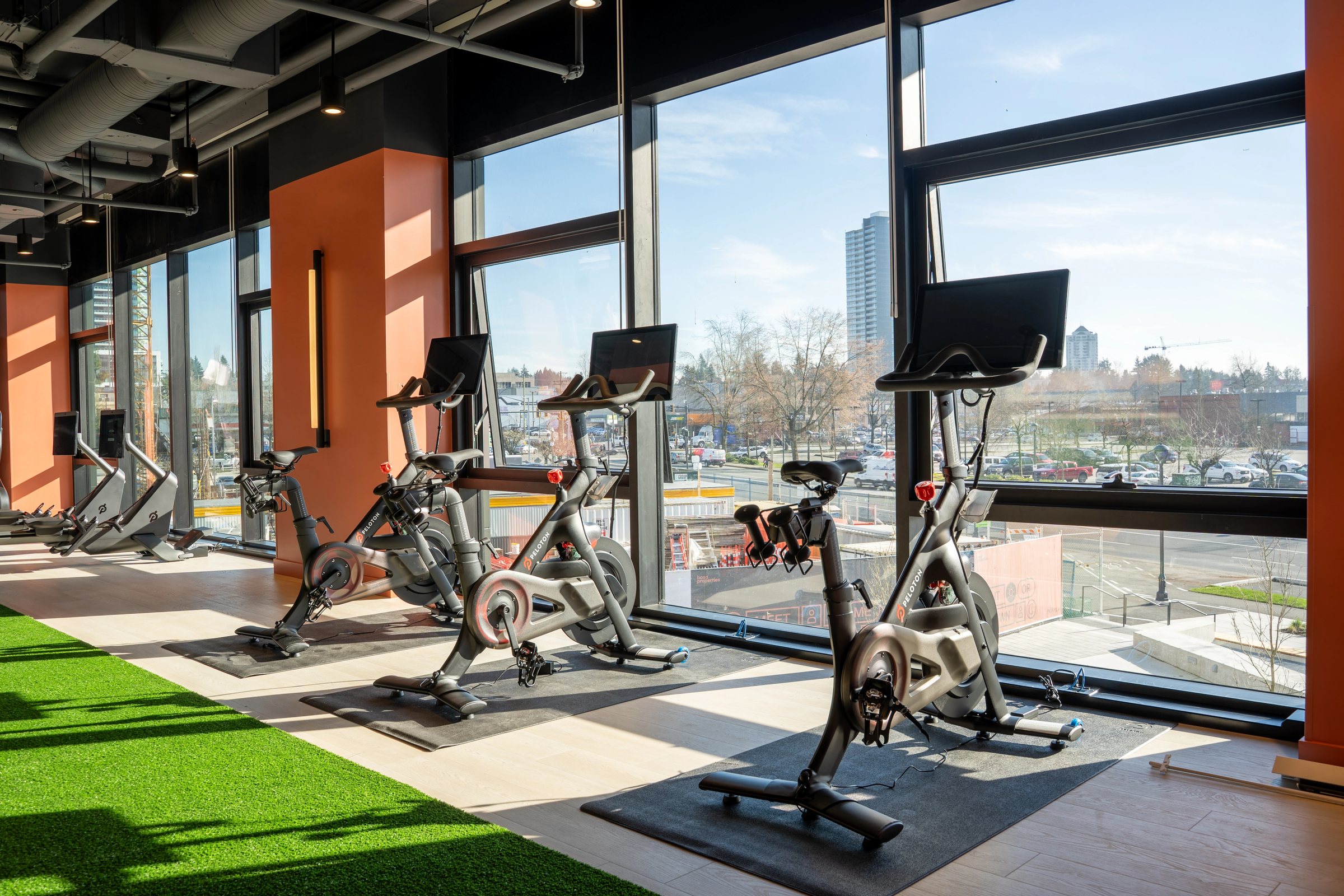Cycling studio at Parkway, a Bosa Properties residential development, with bikes on a turf lane in front of floor to ceiling windows